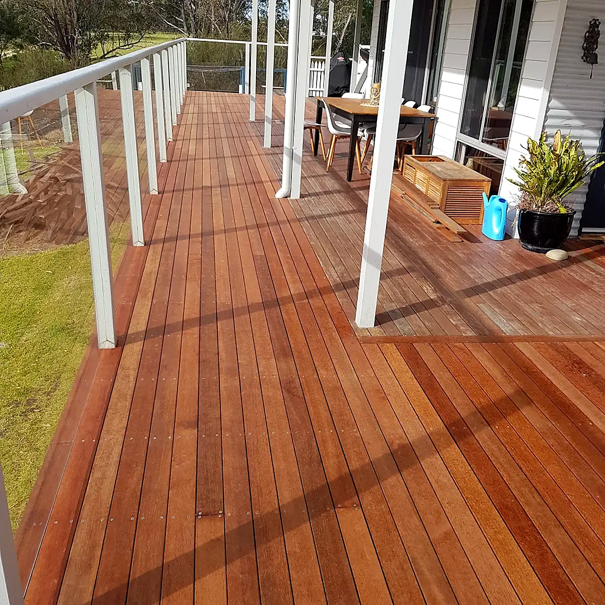 Long timber deck with glass balustrade and outdoor dining setting