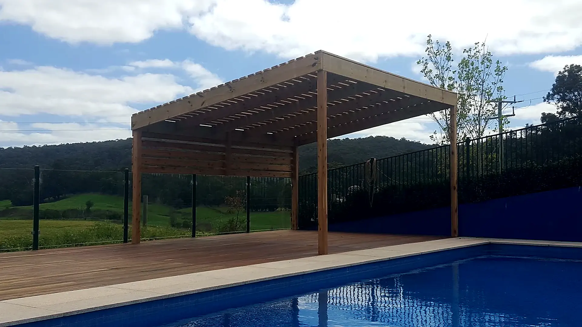 Timber pergola over a pool deck with hills behind, built by Chris Fella Carpentry in East Gippsland