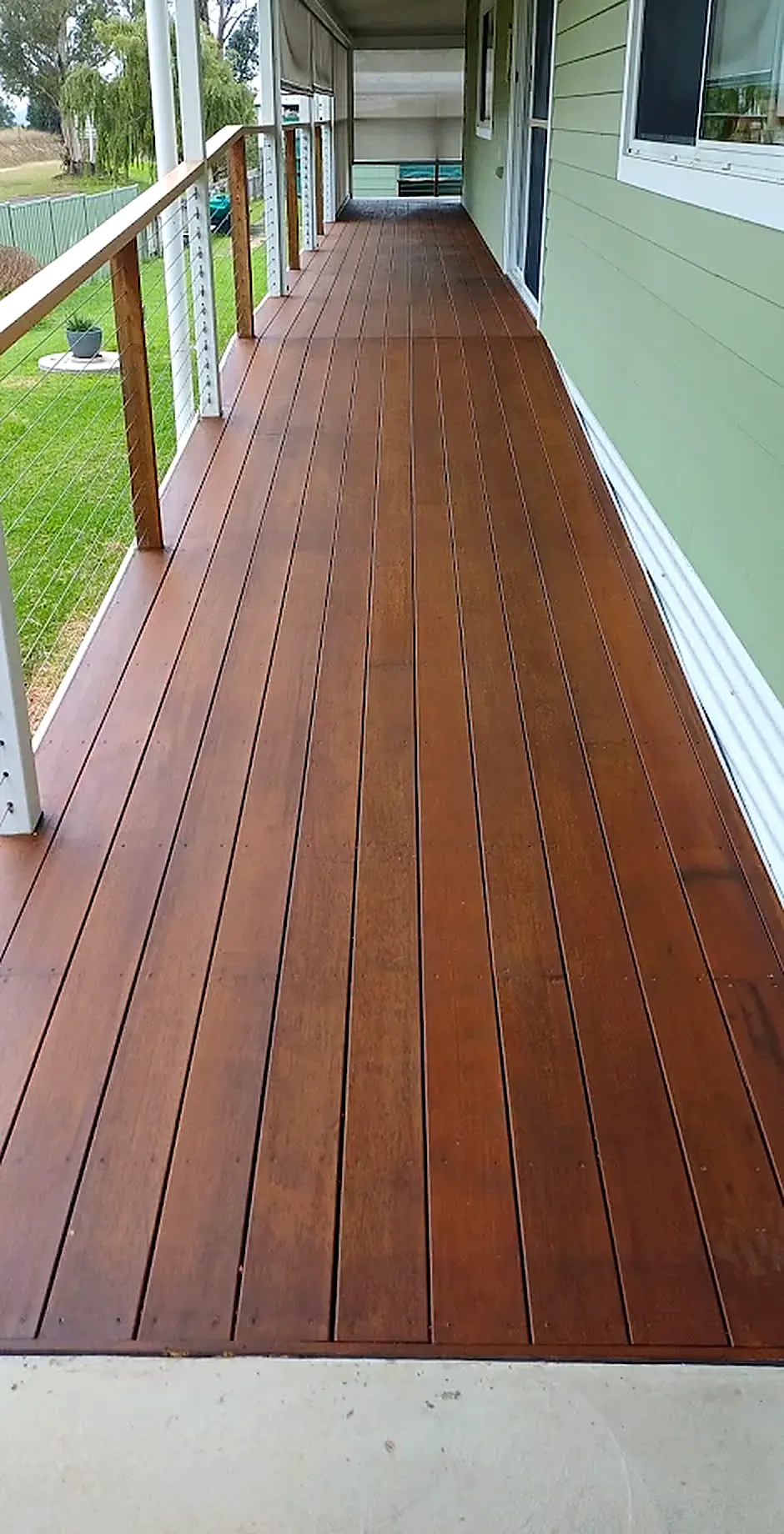 Long verandah deck with painted posts and a timber-capped wire balustrade